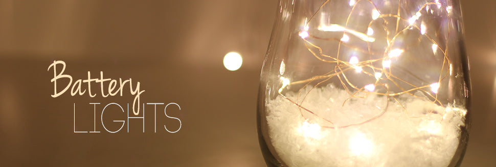 Glass bulb with string lights inside, labeled 'Battery Lights' on a warm-toned background.